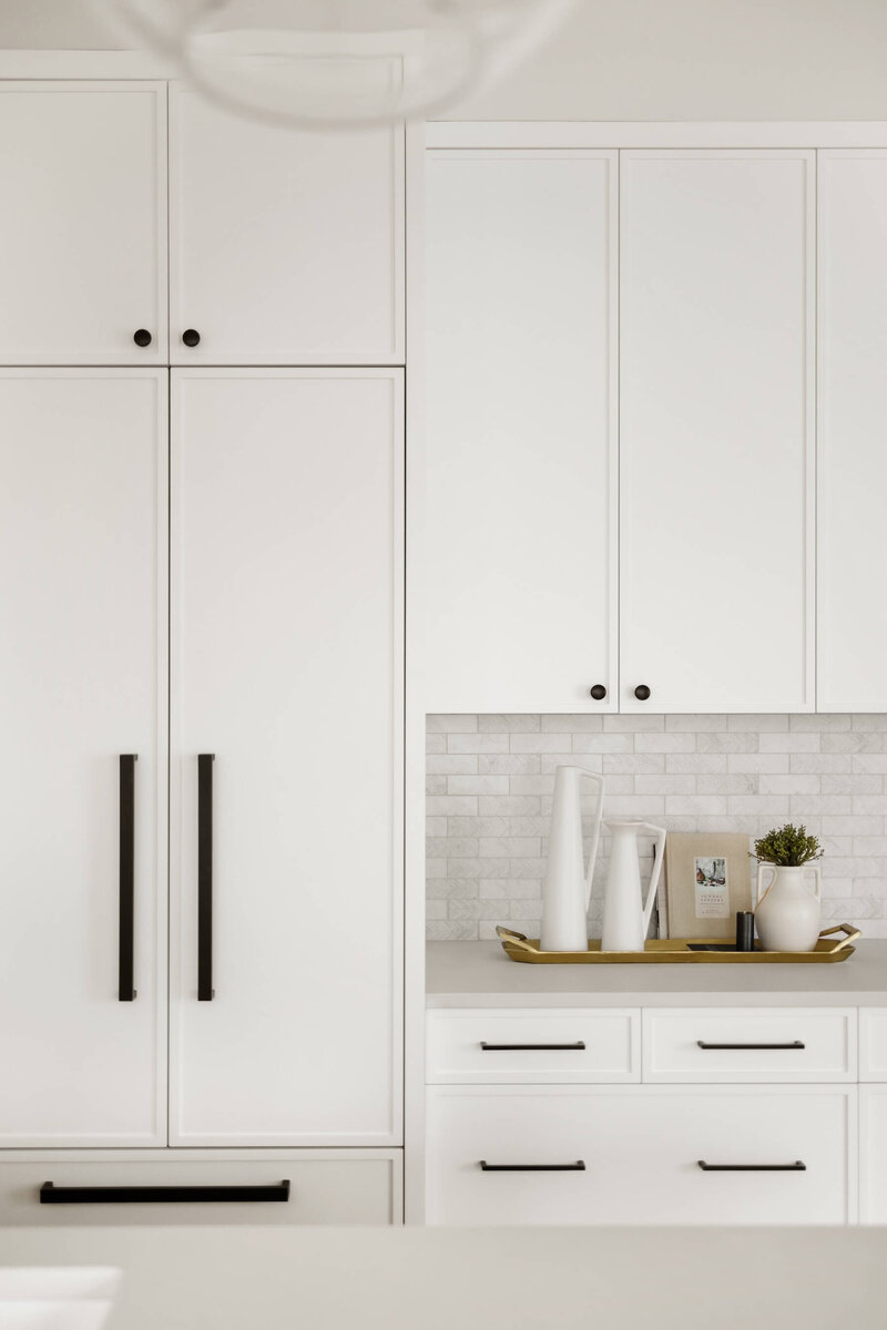 White cabinetry paired with black accents and a panel ready fridge.