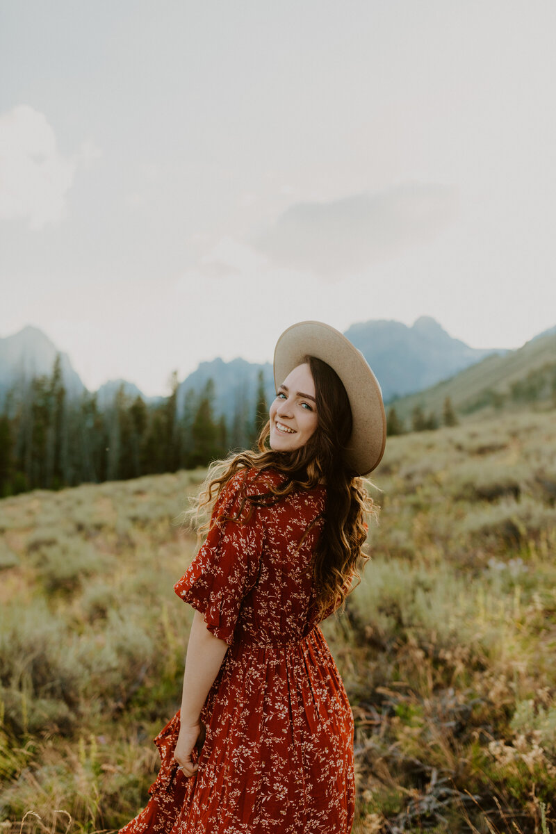 Woman standing in front of mountains with hat on