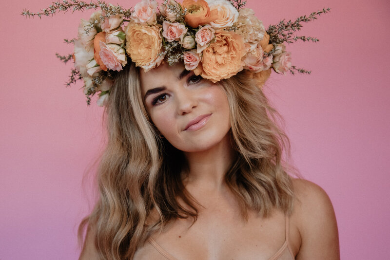  A beautiful model wearing a floral crown looks into the camera 