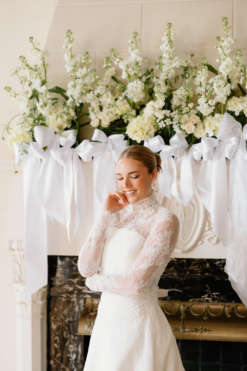 portrait of bride in front of ornate fire place with gorgeous lace gown