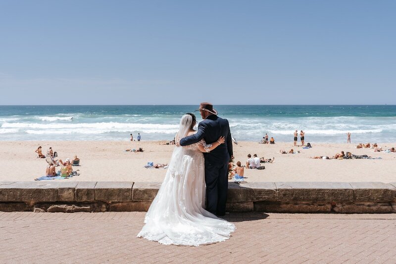 A bride and groom hugging overlooking the beach at Manly