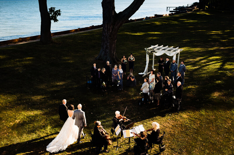 A bride being walked down the aisle by her father with lake Erie in the background. The wedding was at the McIntyre in Monroe Michigan