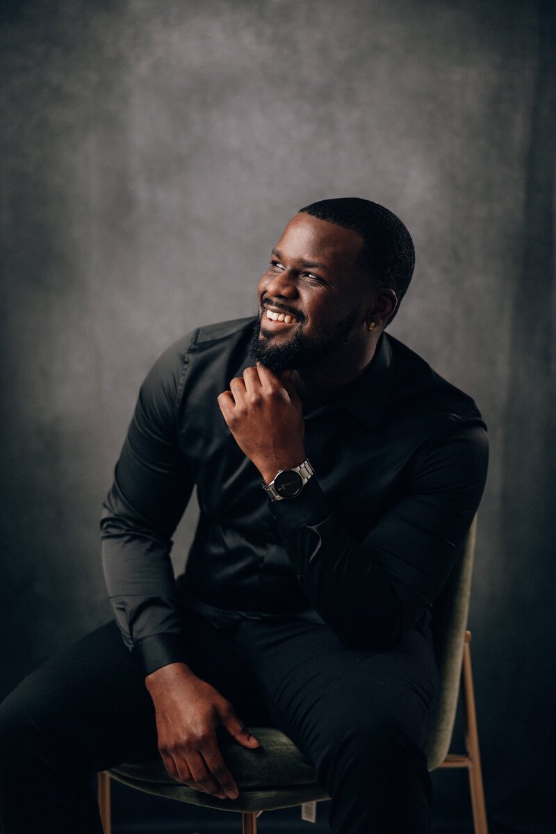 A headshot of an African American photographer smiling and looking away from camera.