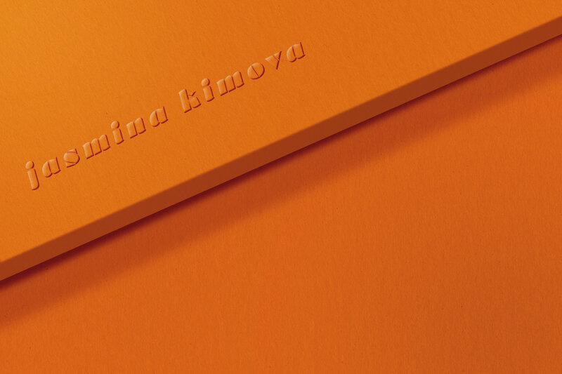 Orange embossed book with ‘kimova’ logo, symbolizing luxury storytelling and studio branding.