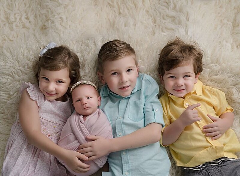 sibling photo , two brothers and two sisters- laying on their back smiling at the camera