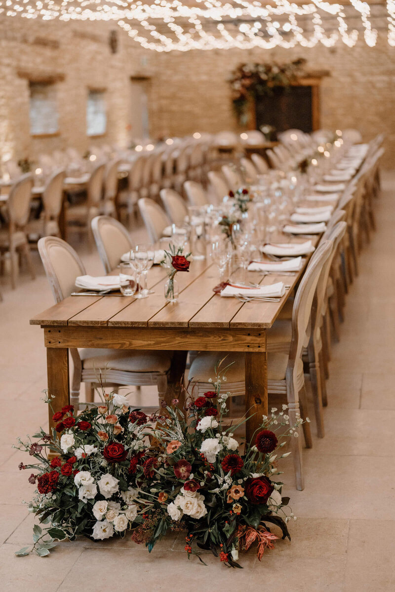 Long banquet-style wedding table with meadow-inspired florals in Caswell House barn