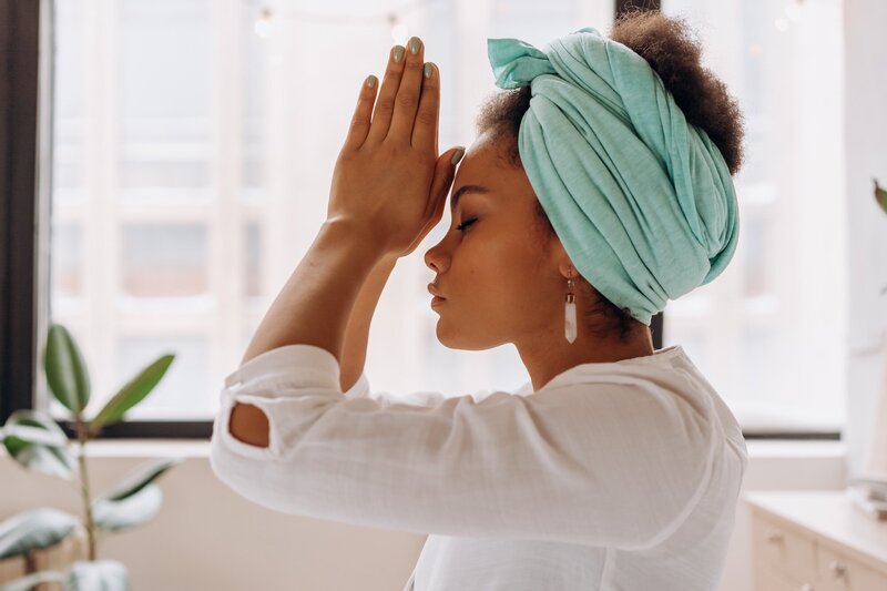 Woman meditating with her hands to her forehead