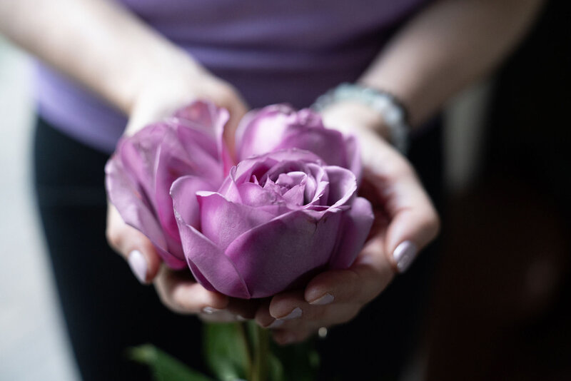 Woman holding a purple rose in her hand