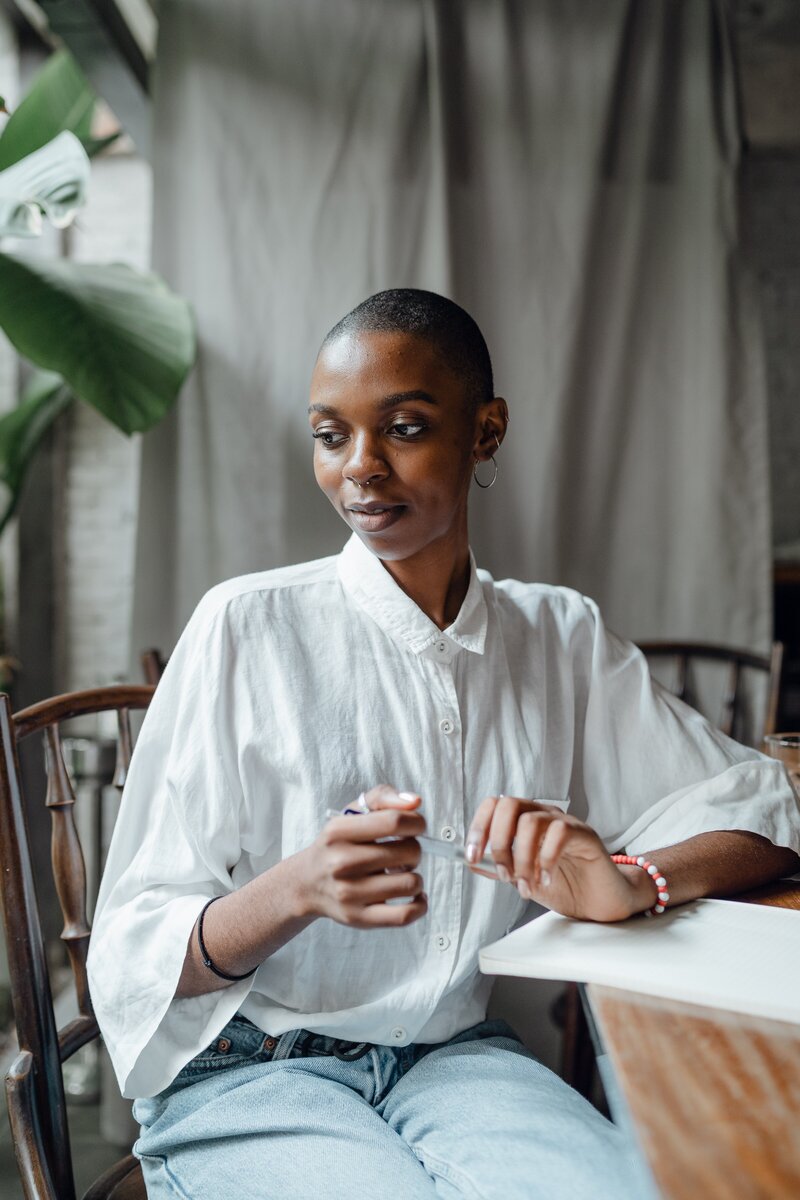 dreamy-trendy-black-woman-sitting-at-table-4350112