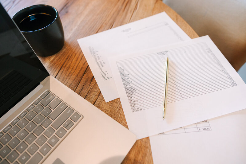 Stack of paperwork next to a lap top
