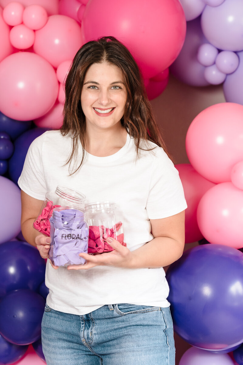 brand photo of a woman among balloons, holding containers full of the balloon