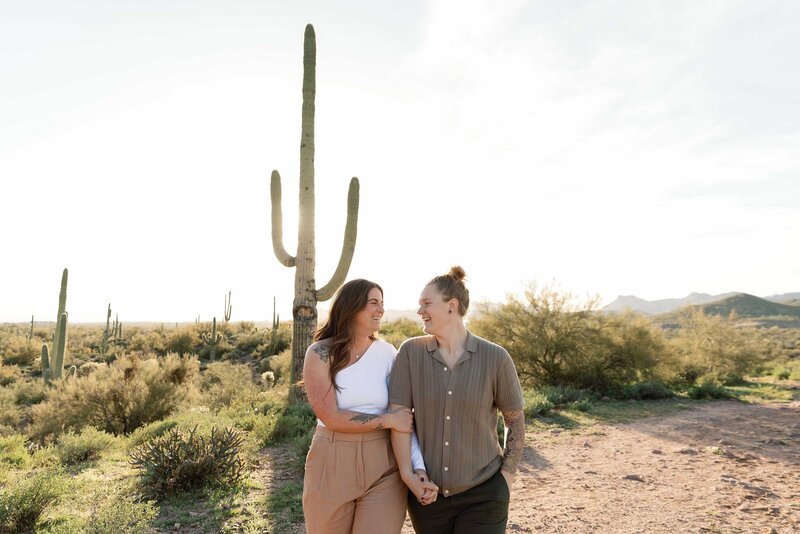 Two women walk hand in hand in the desert for their engagement photos