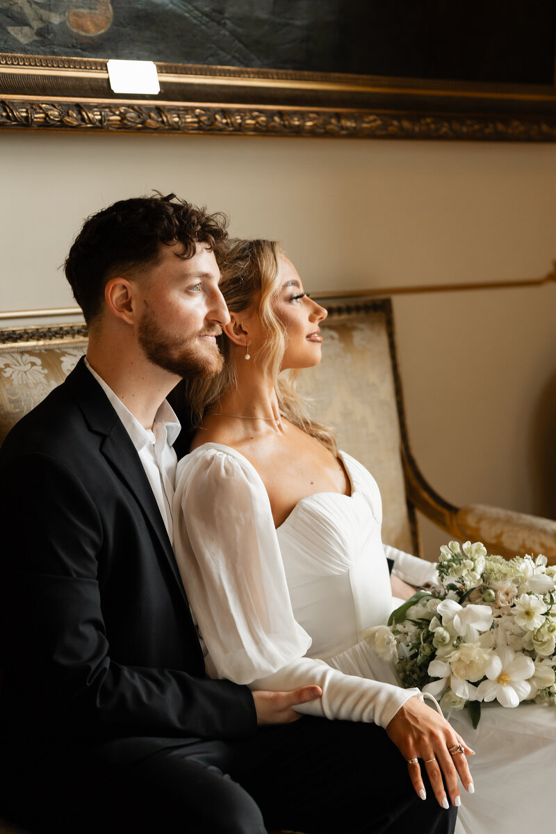 Close-up of the bride sitting in the groom’s lap as they embrace inside their wedding venue, captured in a tender and intimate moment filled with love and connection.