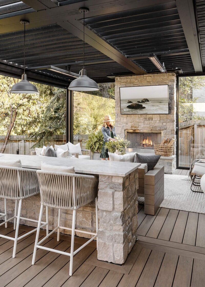 An outdoor bar with stone accents, rattan stools and black pendant lighting. 