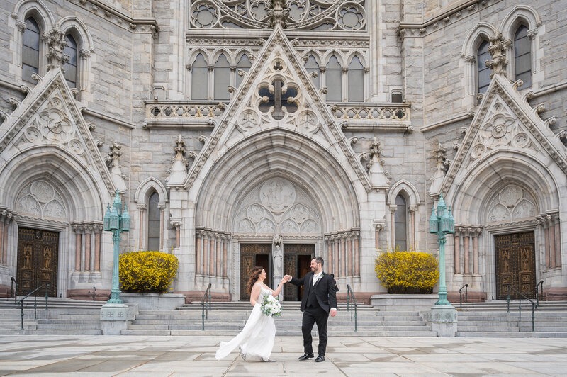 Bride and groom holding hands in front of an ornate church