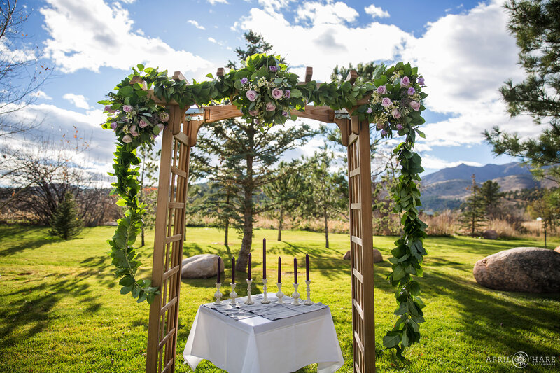 Wood terraced arch decorated with purple florals and greenery for a wedding on the Cabin Lawn at Greenbriar Inn