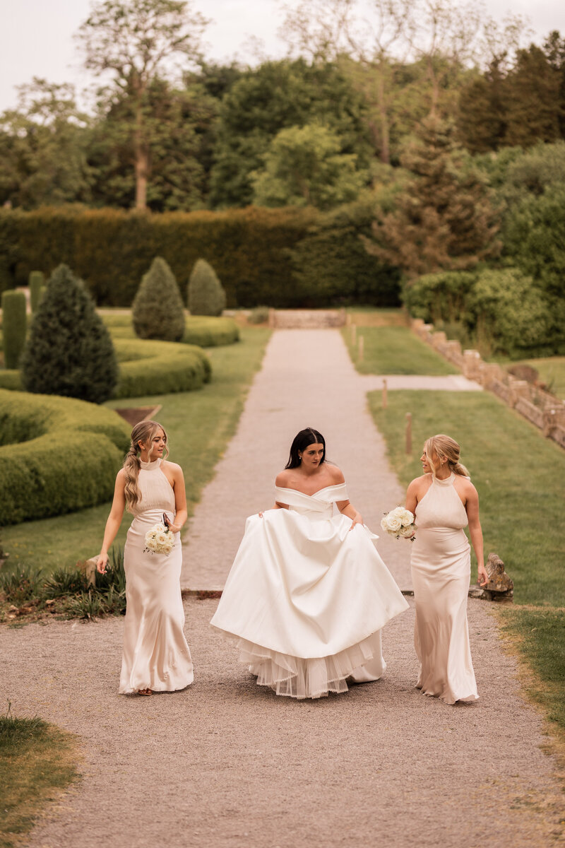 Bride walking with bridesmaids at Cotswolds wedding venue, Tortworth Court