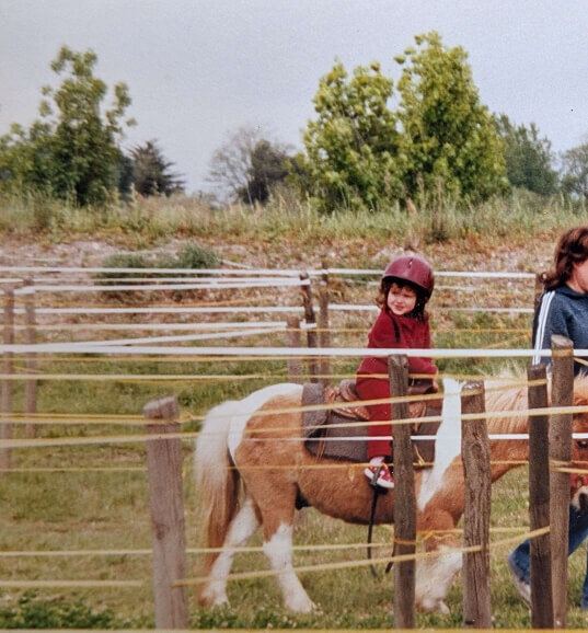 Photo de Colyne, fondatrice du studio créatif, sur un cheval quand elle était petite.