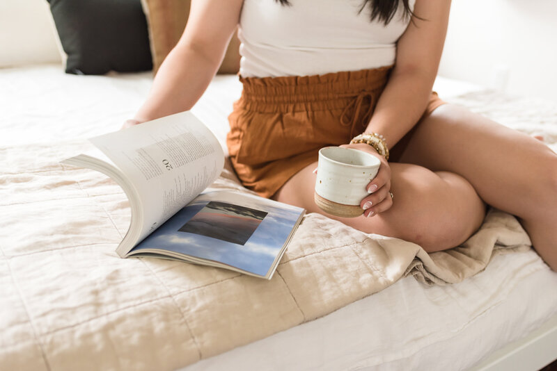 Woman sitting on a bed with coffee and a book