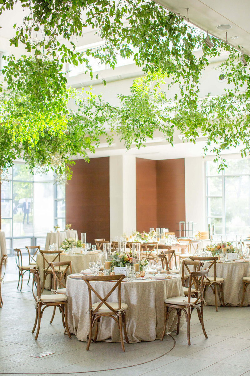 Image shows a wedding reception with a ceiling bedecked in smilax greenery.