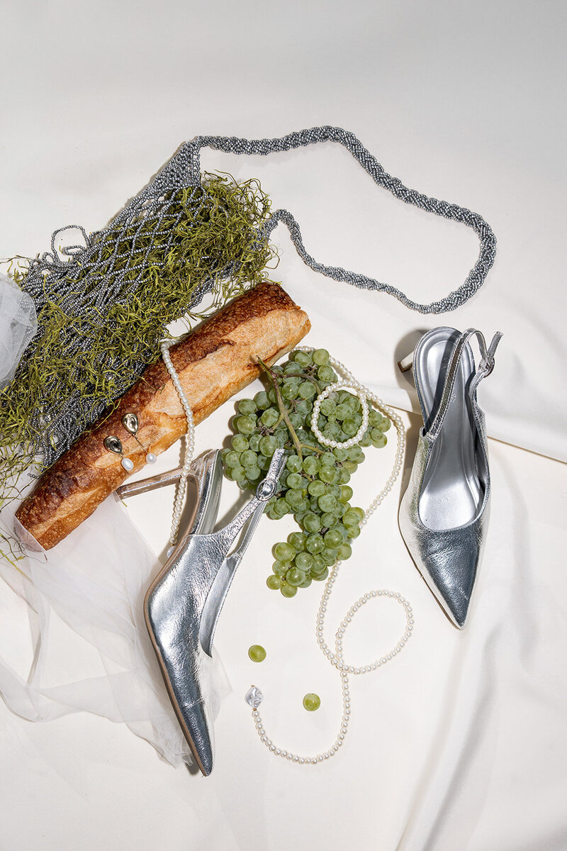  Editorial wedding details photo featuring a white silk ribbon, olive branch, and accessories, typical of a global luxury destination wedding.