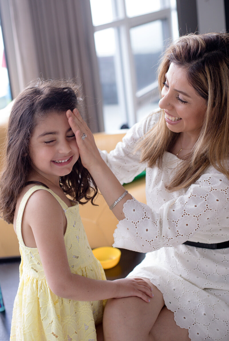 woman-sits-and-pulls-the-hair-back-from-a-childs-face