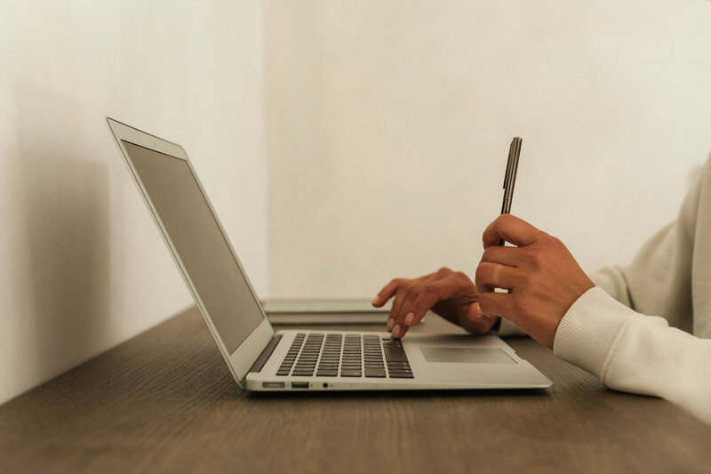 typing on a laptop while holding a pen