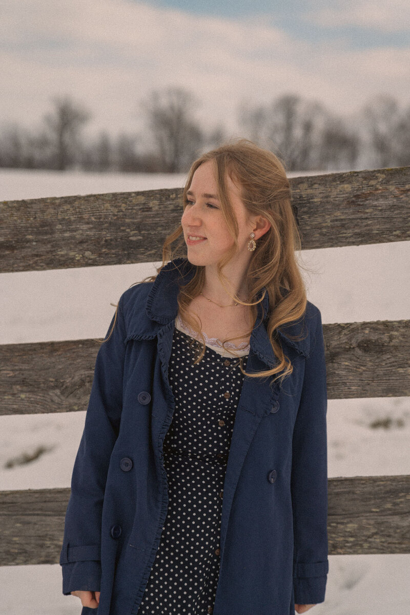 Pregnant mother standing in the snow and looking at her belly at a maternity photo session in westerville ohio