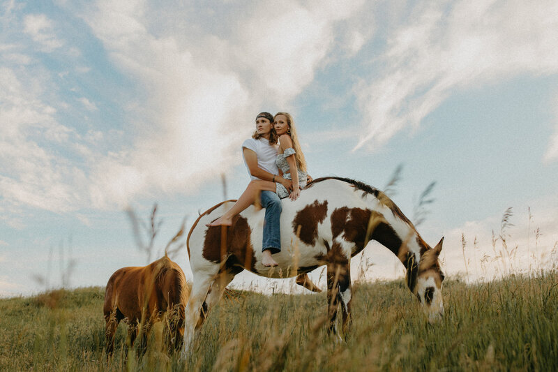 Couple sitting bareback on a horse at sunset.