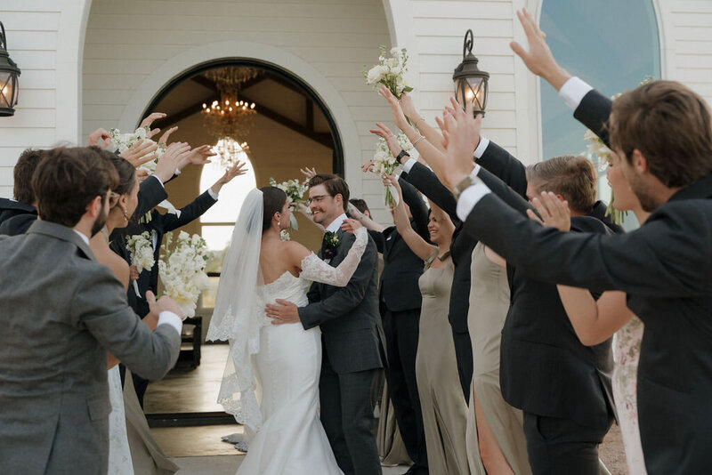 Bride and groom with their bridesmaids and groomsmen, dressed in pink spring dresses and suit attire with a Texas hill country background