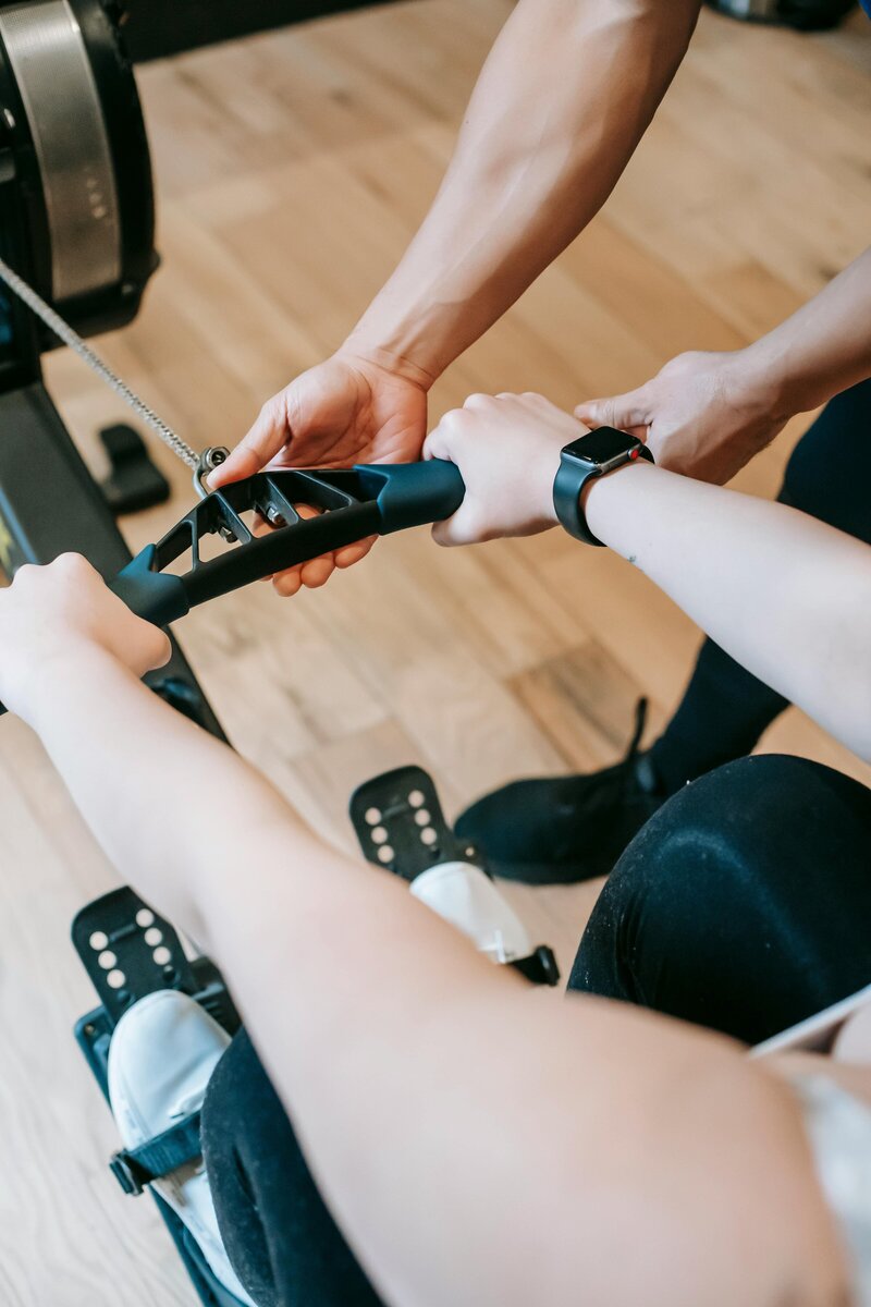 personal trainer opastamssa soutulaitteen käyttöä