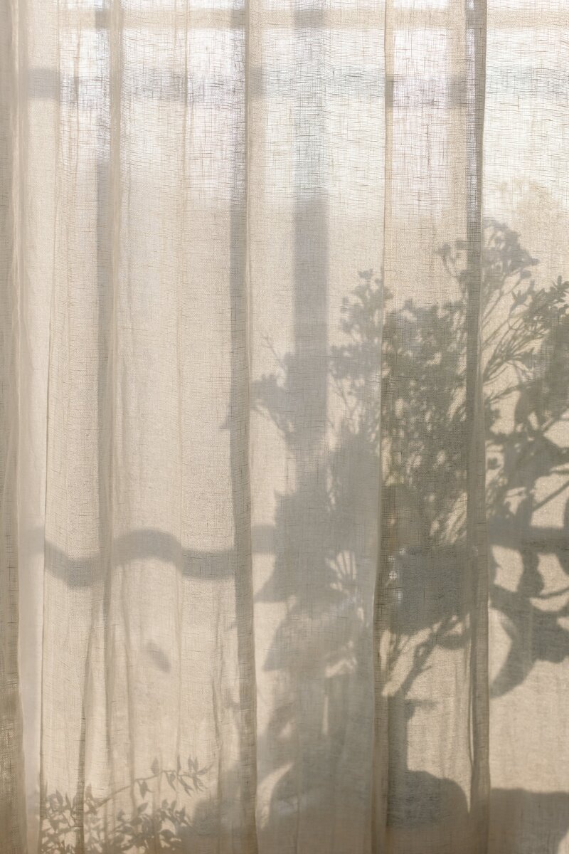 A cotton curtain with ominous shadows cast over it.