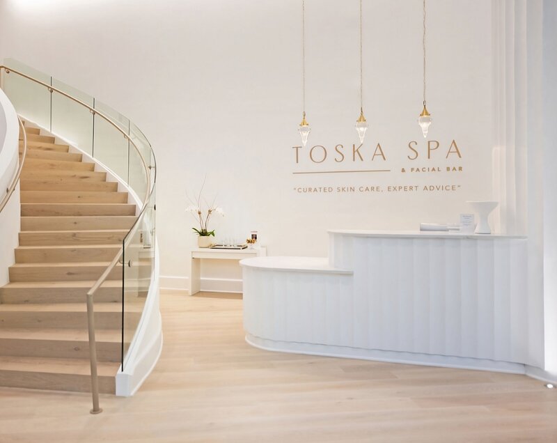 Light, airy spa interior with Toska Spa brand signage and minimalist design aesthetic