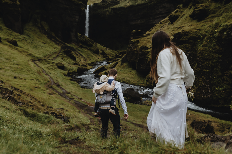 Couple eloped with their child to Iceland and walking towards a waterfall