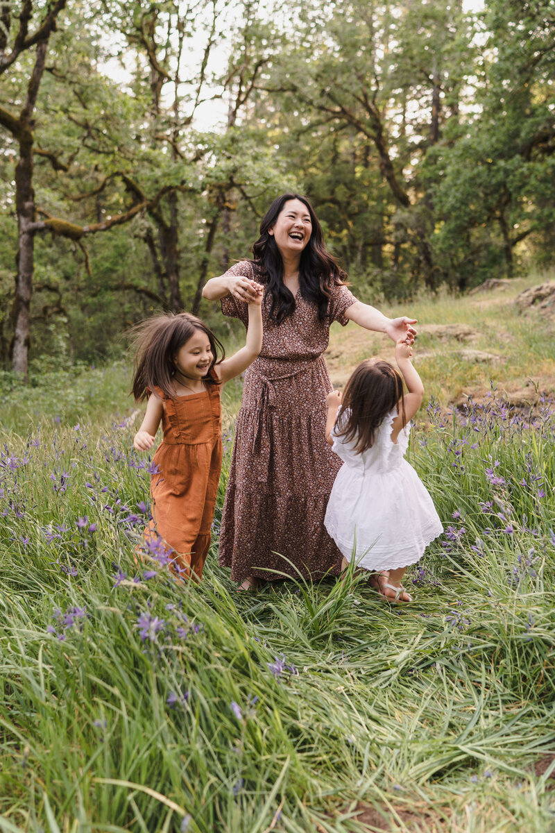 A mom and her two daughters dancing on a wild flower filed in Portland