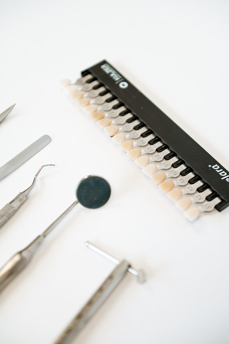 A close up of an array of dental tools and a tooth color swatch  palette