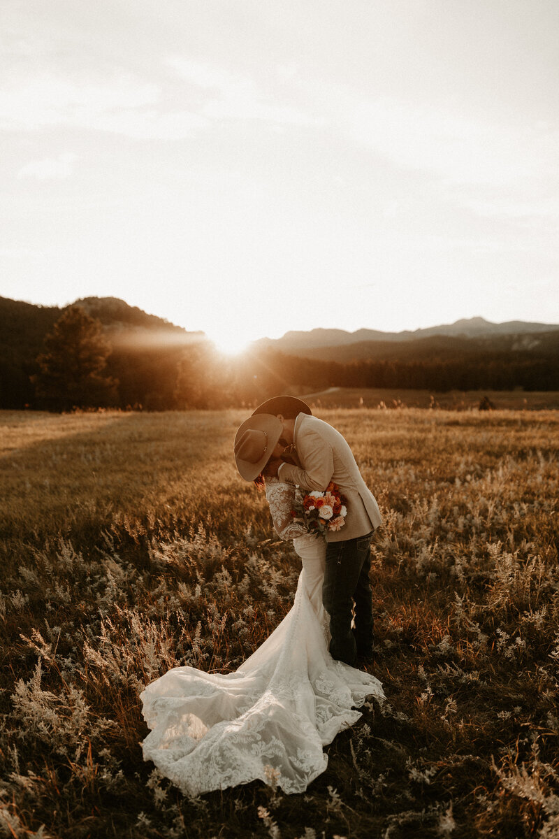 bride and groom kissing, cowboy hats covering their faces at sunset in the Black Hills National Forest, South Dakota