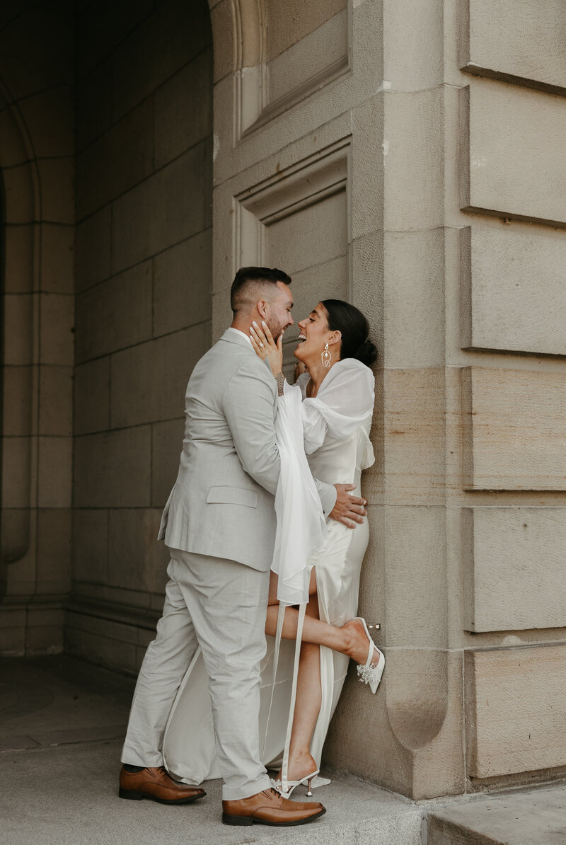 Bride and groom holding each other's faces and laughing