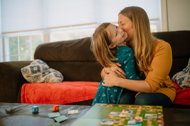 Girl hugging her mom after winning a board game.