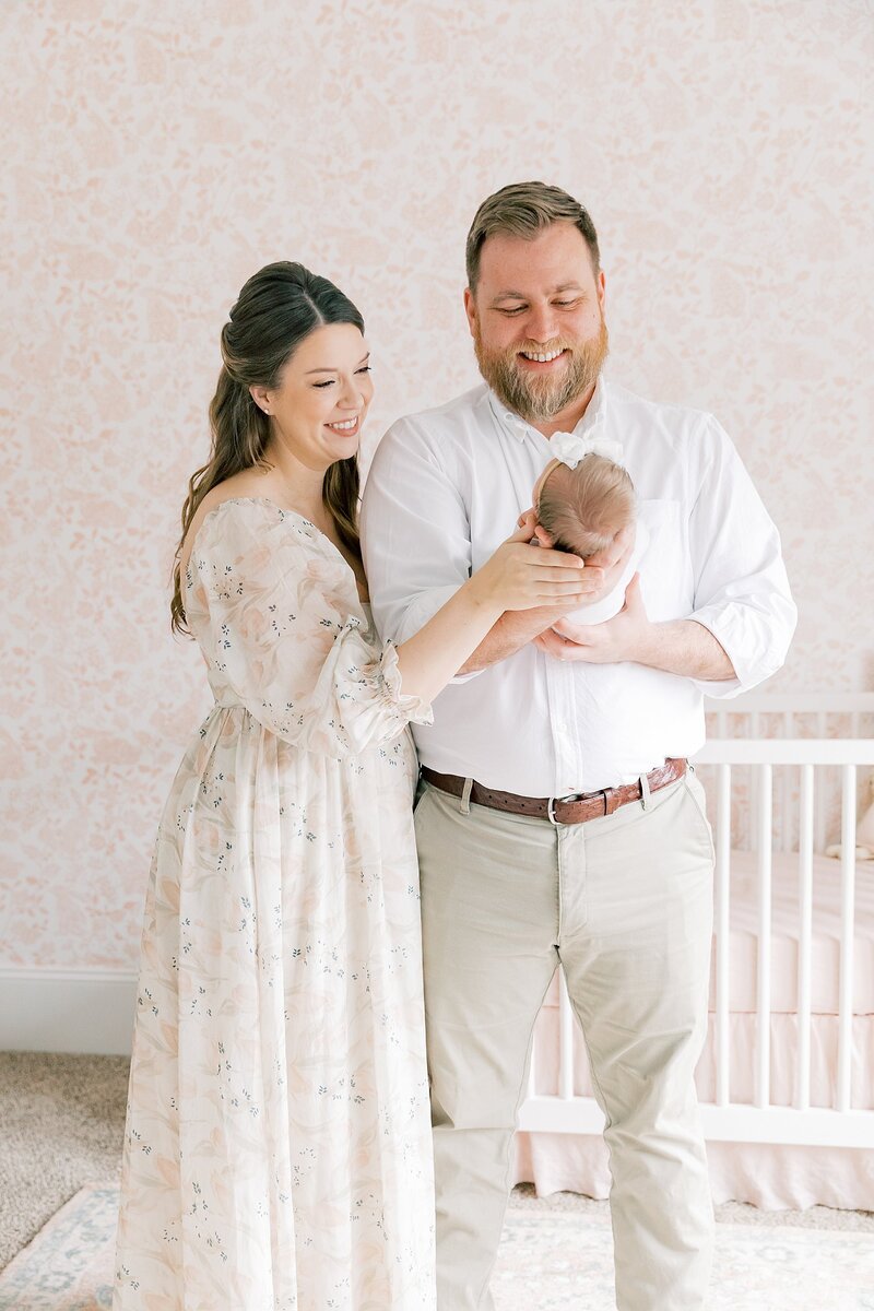 A man and woman posing in front of a baby's nursery for a newborn photographer.