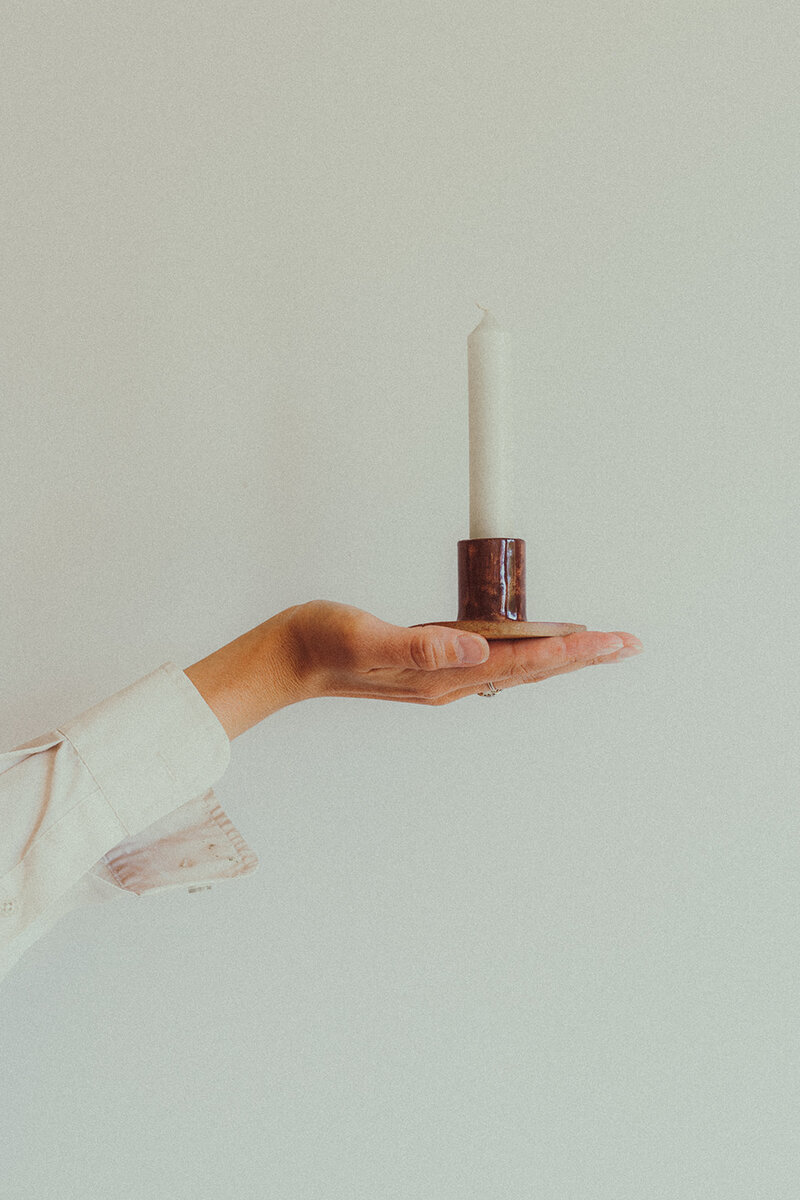 a woman holding a candle in a handmade candle stick holder