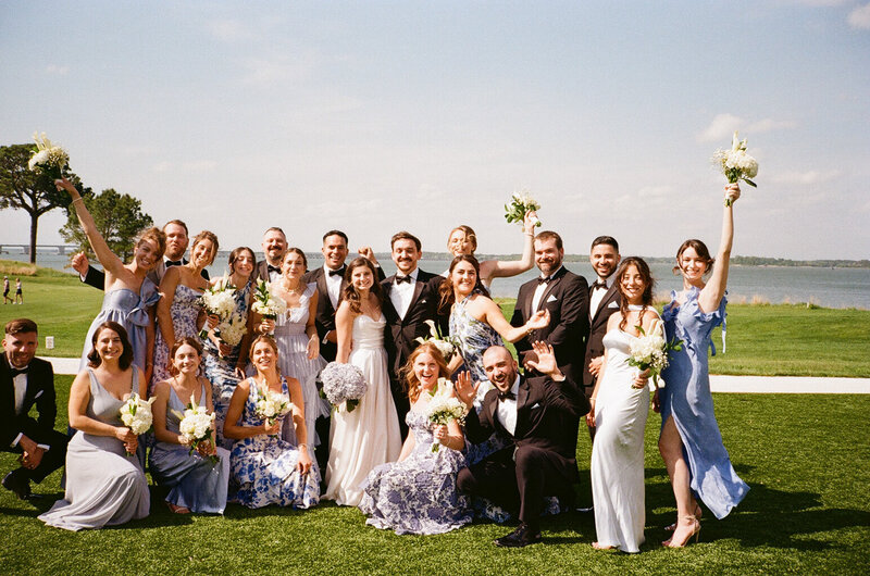 A large wedding party celebrates with the newlyweds on Chesapeake Bay