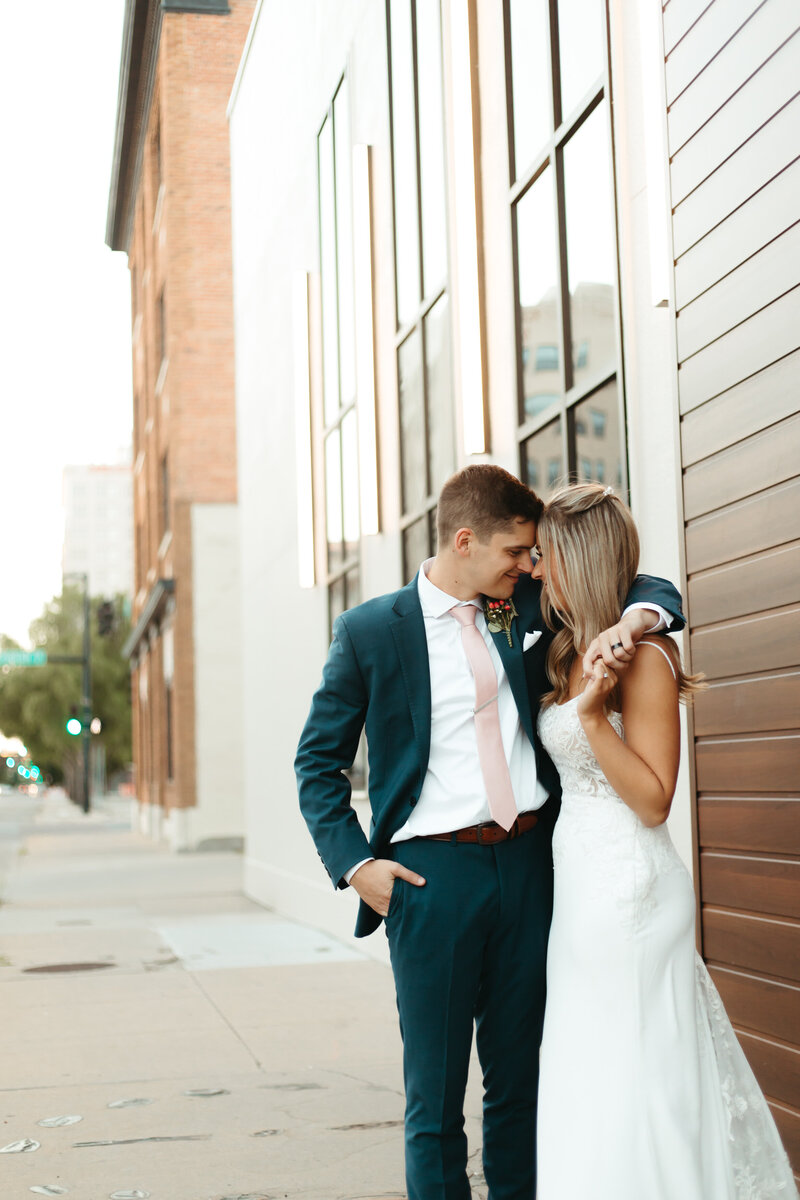Bride and Groom cuddle up during their summer bridal portraits at Brick and Mortar Venue in Downtown Wichita Kansas after their Wedding with Ashley Cole Photography