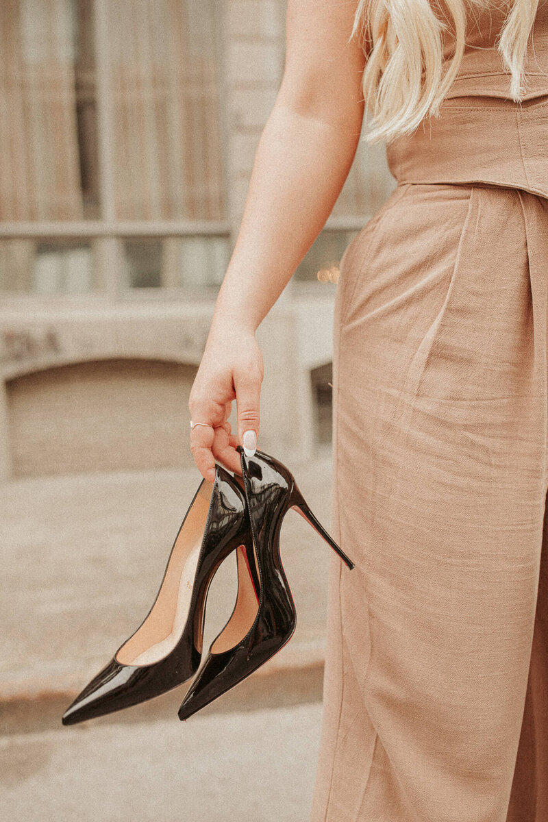 business speaker and influencer natasha zoryk holding black heels in front of a city building