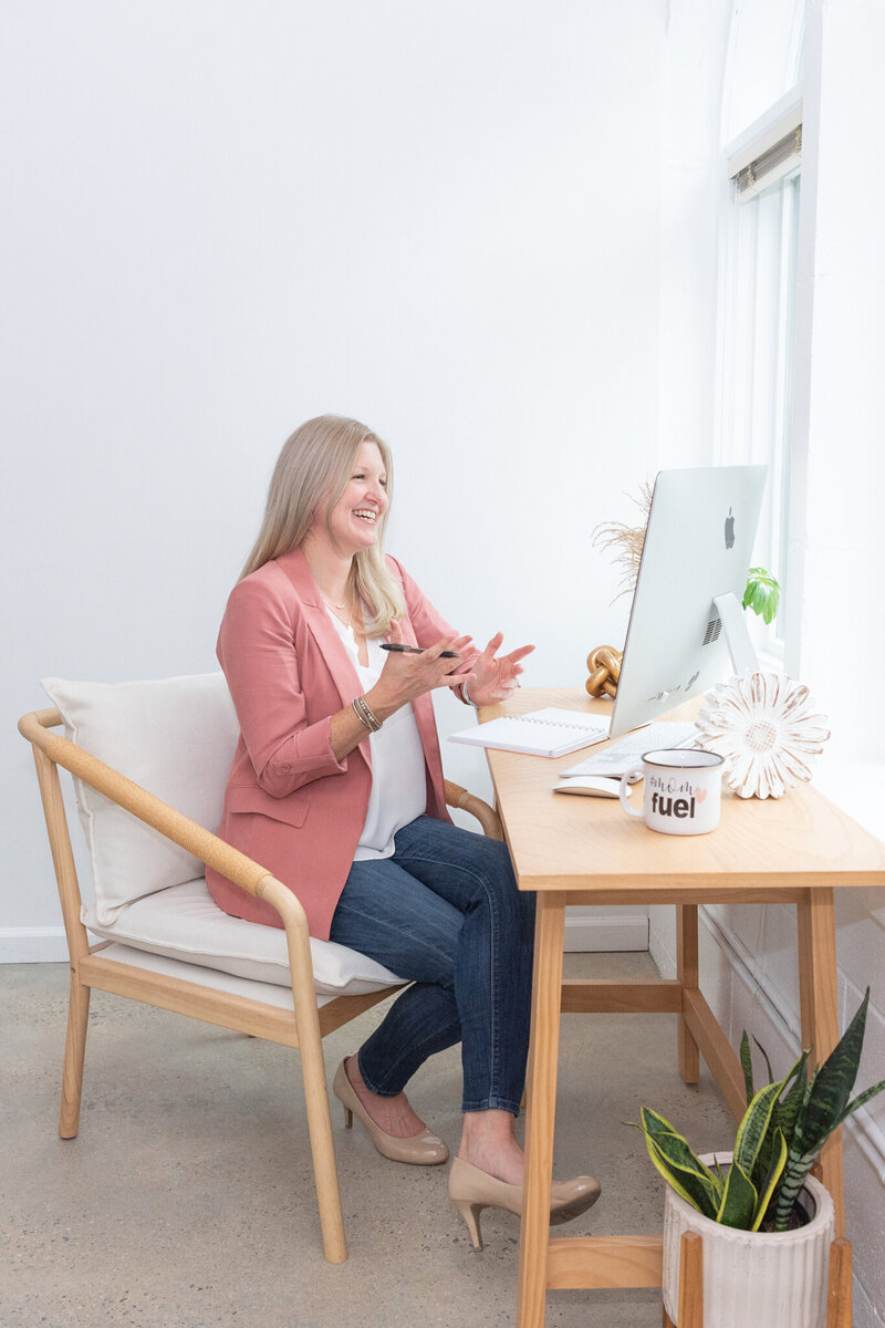 Maureen sitting at desk talking to custom web design client via Zoom call