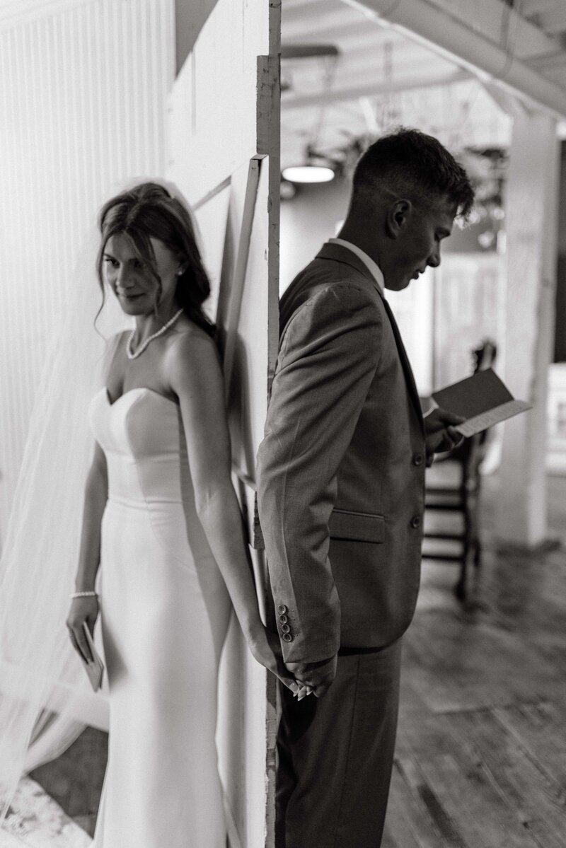 bride and groom stand back to back with a door between them while they read their vows to each other