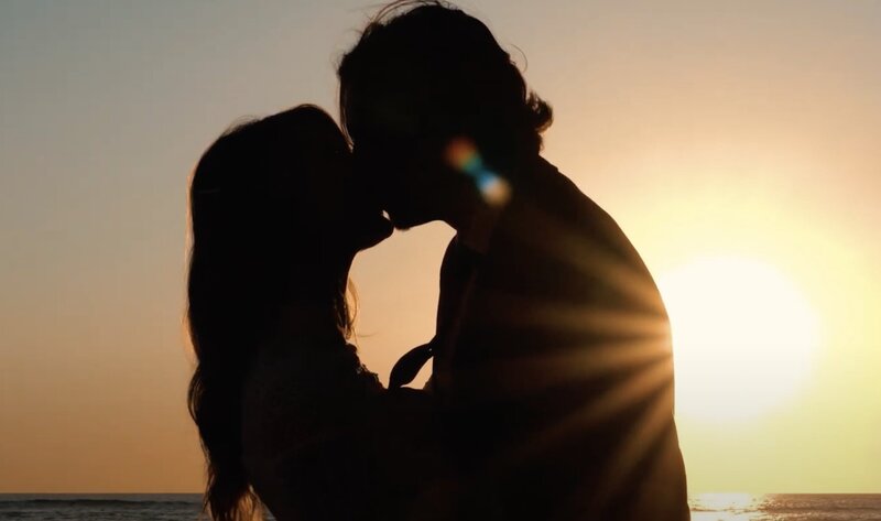 A couple kissing with the sun silhouetting them 