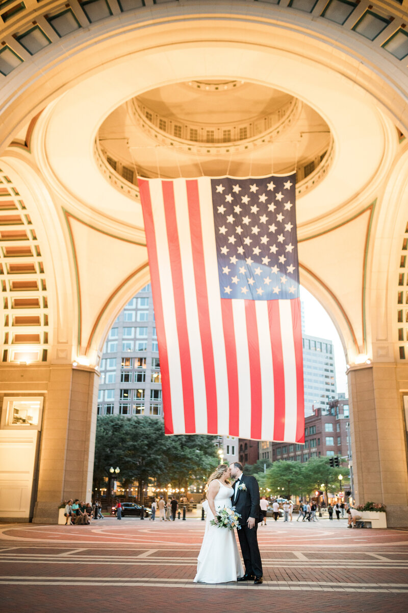 Wedding couple kissing under American flag at Boston Harbor Hotel