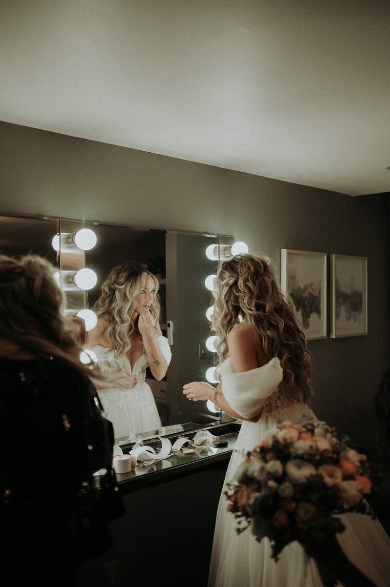 A bride looking in the mirror all ready putting final lipstick touches on herself.