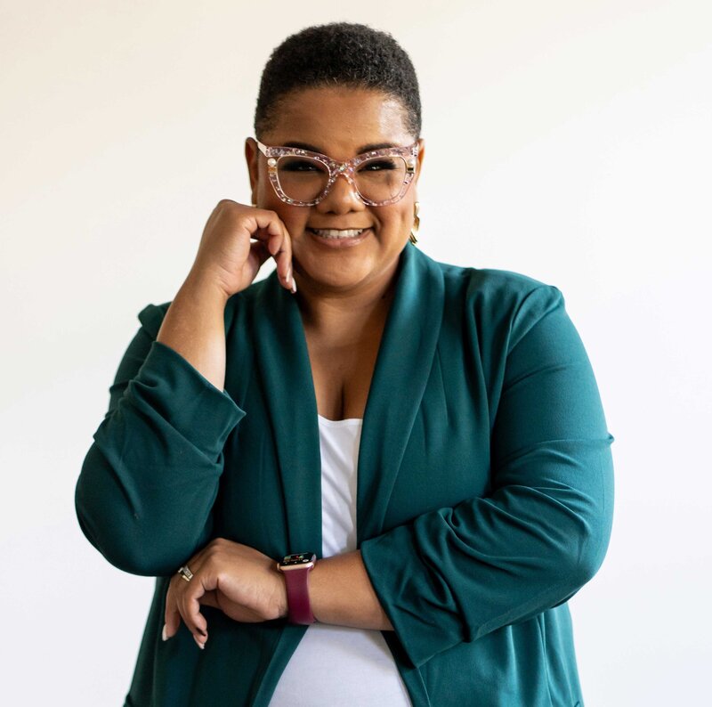 Professional woman wearing a green blazer and reading glasses, representing executive coaching for women aiming to advance their careers